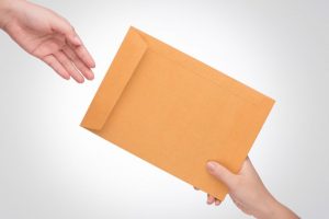 Hand passing envelope to another hand