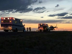 Two Ambulances Pulling Up to A Helicopter During Sunset