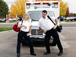 Paramedics posing in front of an ambulance holding medical bags