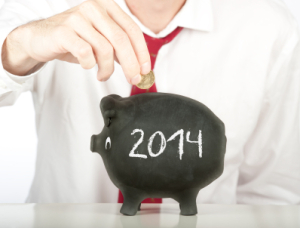 a person in a suit putting a coin into a pig bank with 2014 written on the side of it