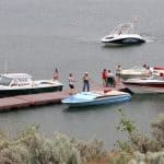 people standing on a dock with boats tied up