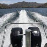 boat engines and wake with mountains in the background.