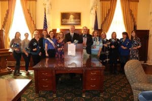 Prosecutor Jan Bennetts and Governor Brad Little pose with a group of people and smile to proclaim April as Child Abuse Prevention Month.