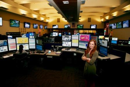 911 Dispatch Center worker standing in front of her desk